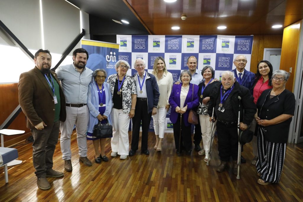 Fotografía grupal de 13 personas. 8 Líderes Mayores y autoridades del Biobío